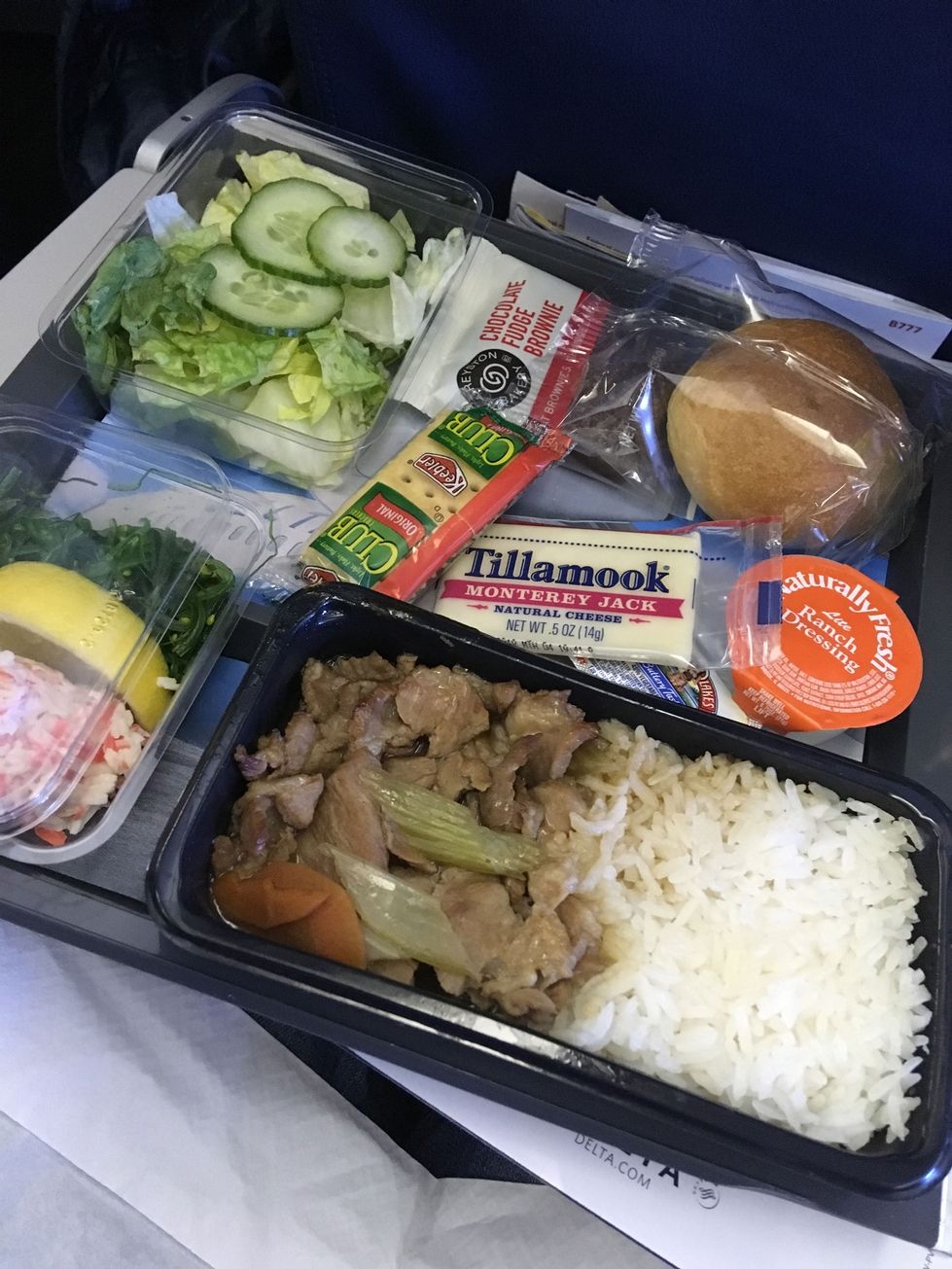 Meal with pork, rice, salad, roll, and brownie